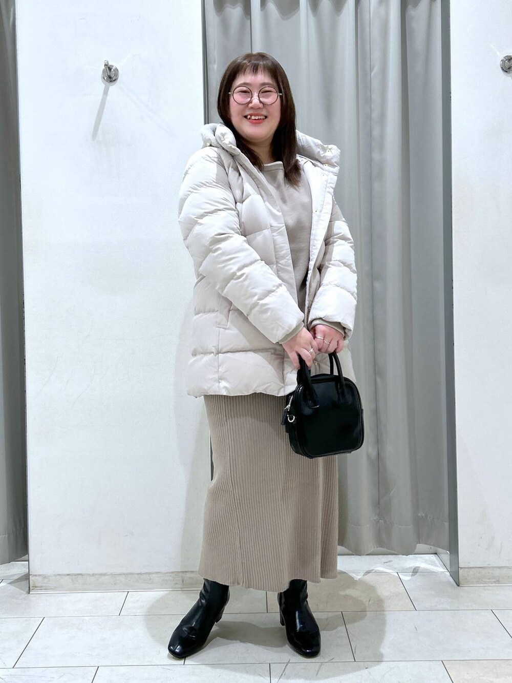 ベージュ系のダウンジャケット/コート、ブラック系のブーツ、ブラック系のボストンバッグを着用したレディースの冬コーディネートの4枚目の写真