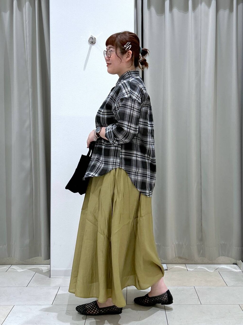 グリーン系のキャミソール、ブラック系のトートバッグ、イエロー系のスカートを着用したレディースの夏コーディネートの4枚目の写真