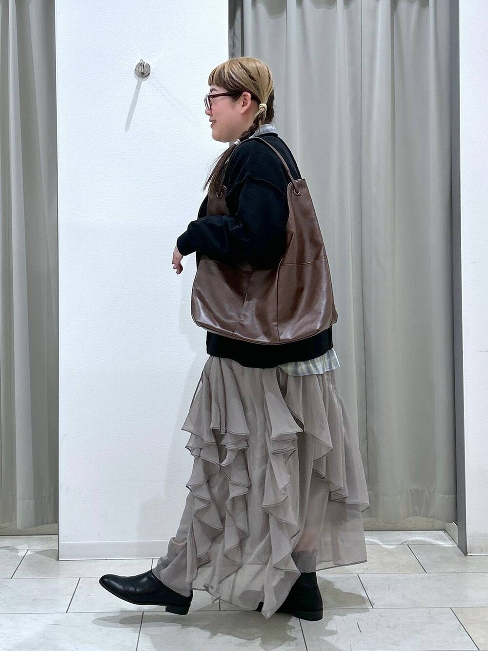 グリーン系のシャツ/ブラウス、ブラック系のブーツ、ブラウン系のトートバッグを着用したレディースの冬コーディネートの3枚目の写真