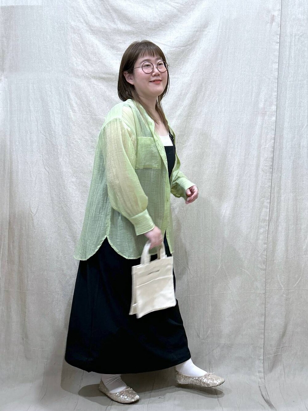 ホワイト系のタンクトップ、ブラック系のジャンパースカート、ホワイト系のバレエシューズを着用したレディースの春コーディネートの5枚目の写真