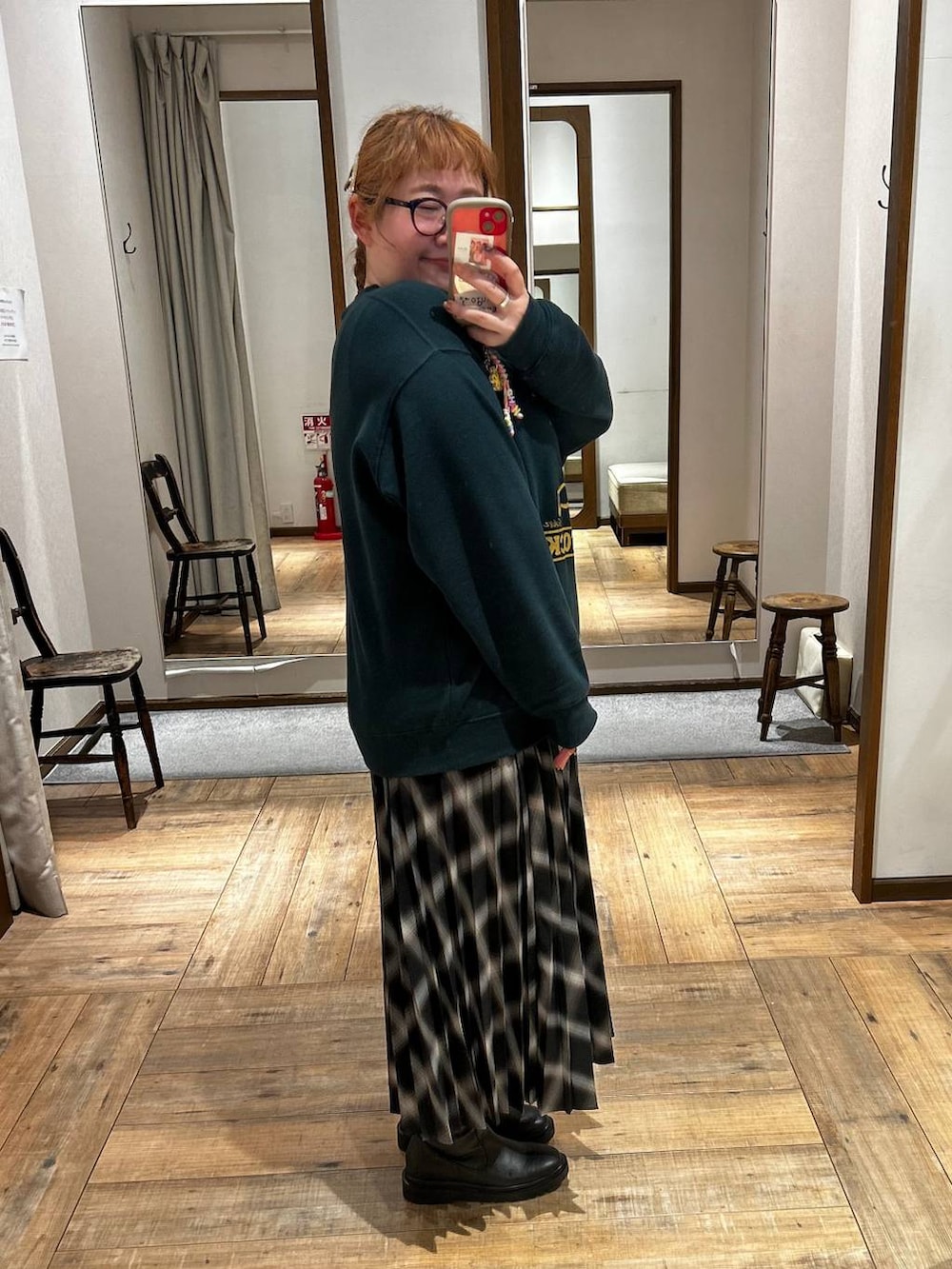 ブラック系のブーツ、グリーン系のスウェット、ブラック系のスカートを着用したレディースの秋コーディネートの2枚目の写真