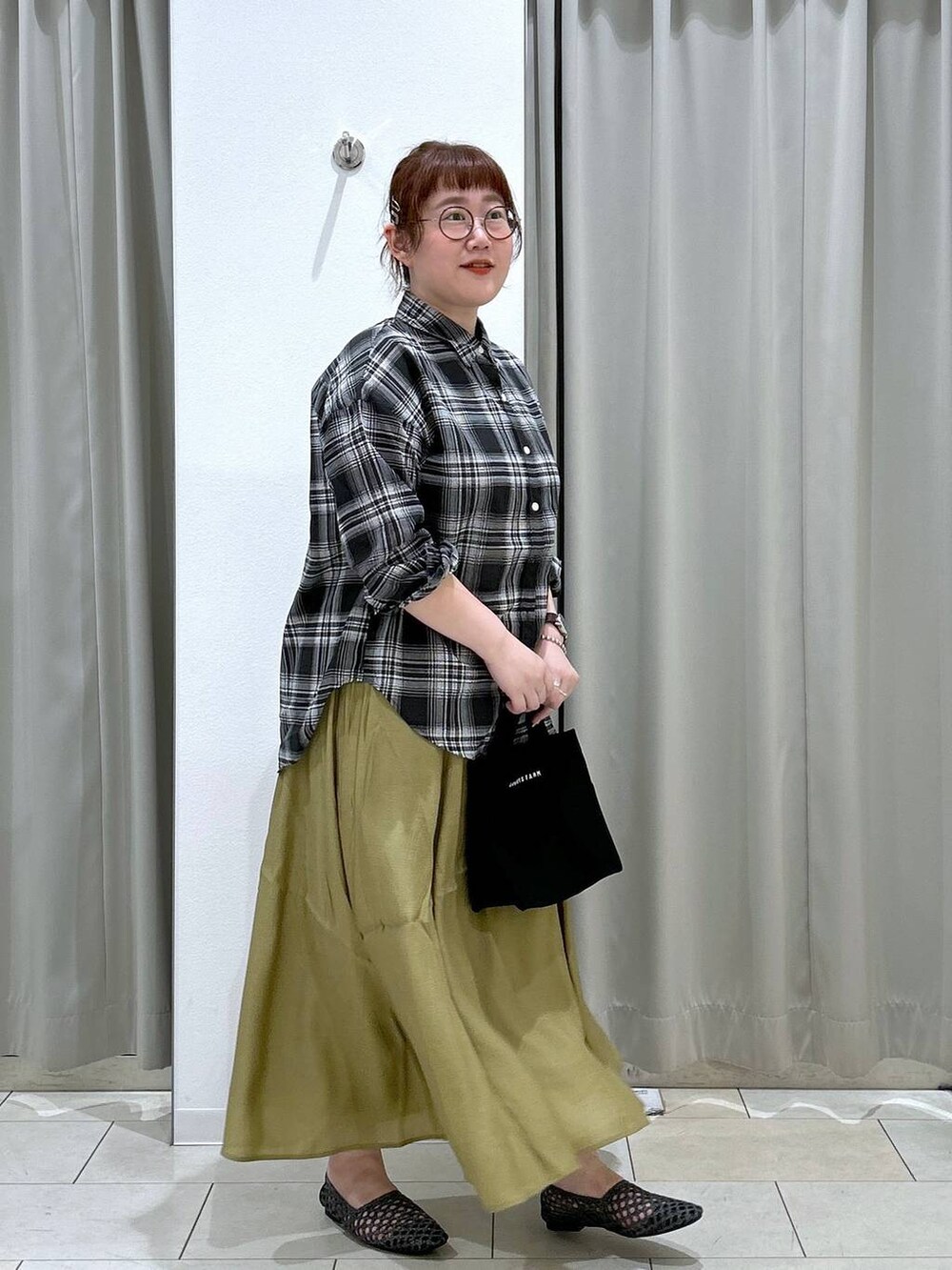 グリーン系のキャミソール、ブラック系のトートバッグ、イエロー系のスカートを着用したレディースの夏コーディネートの6枚目の写真