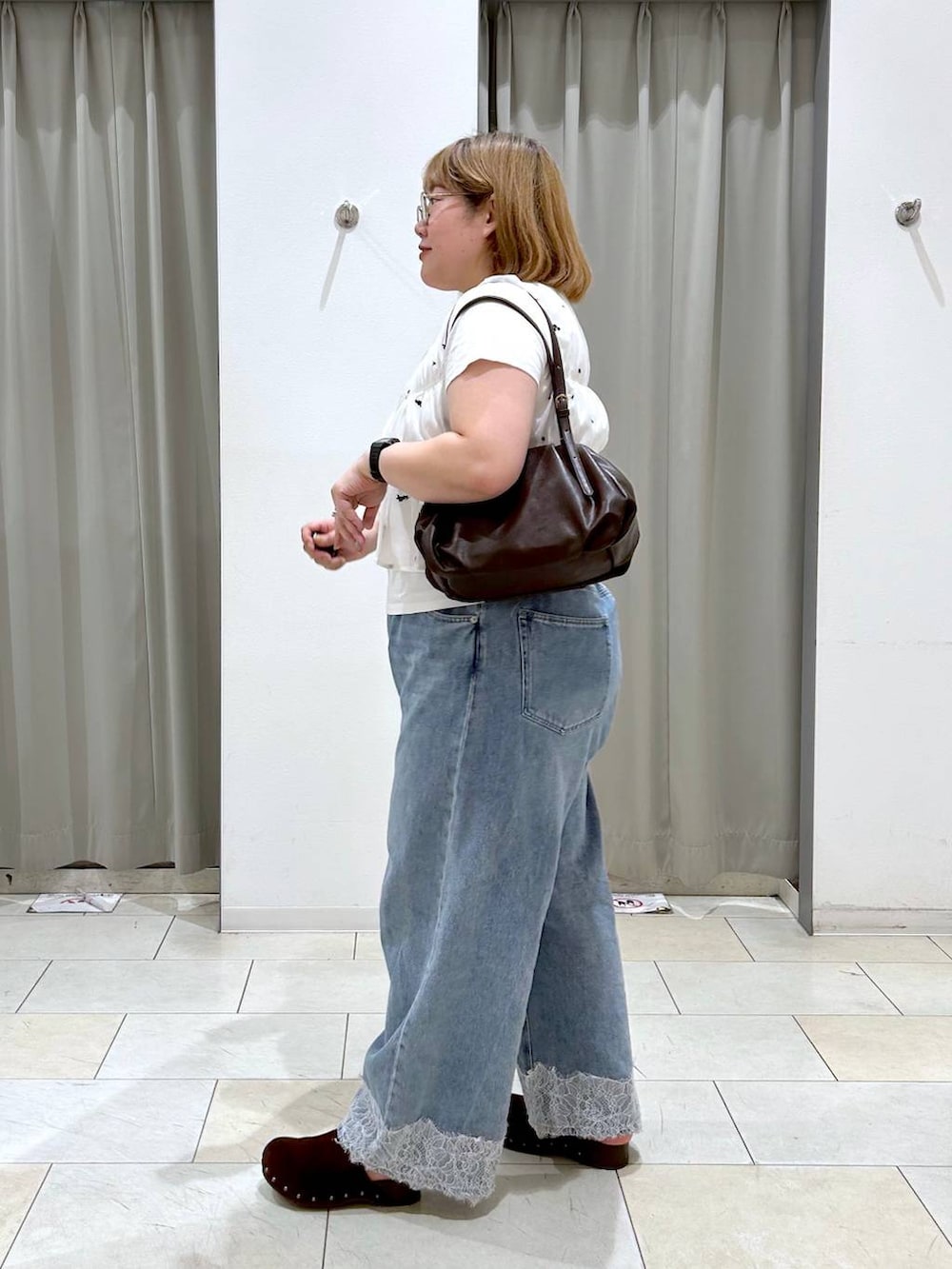 ブルー系のデニムパンツ、ブラウン系のボストンバッグ、ブラウン系のサンダルを着用したレディースの夏コーディネートの3枚目の写真