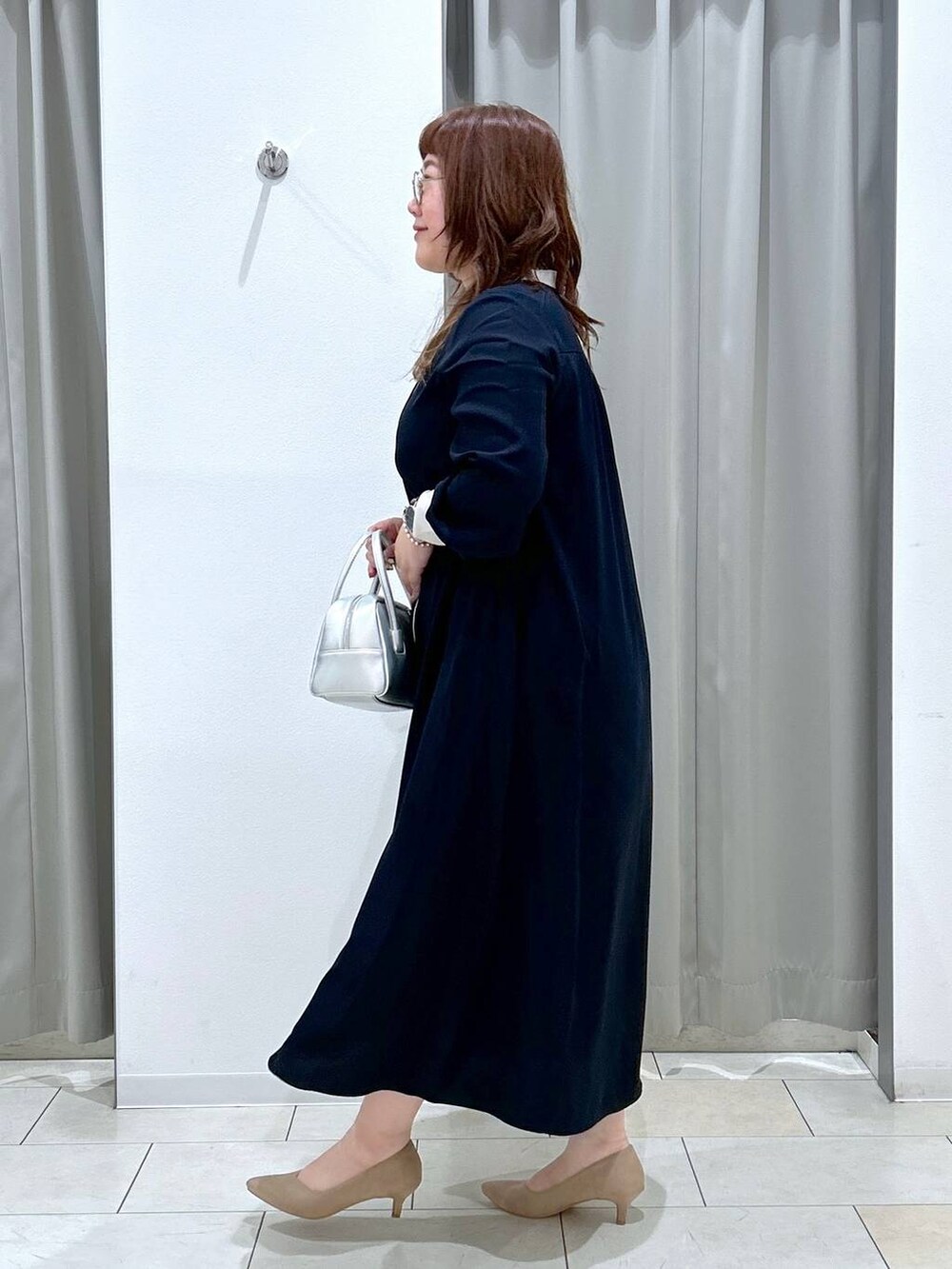 ブルー系のワンピース、ベージュ系のパンプス、シルバー系のボストンバッグを着用したレディースの秋コーディネートの5枚目の写真