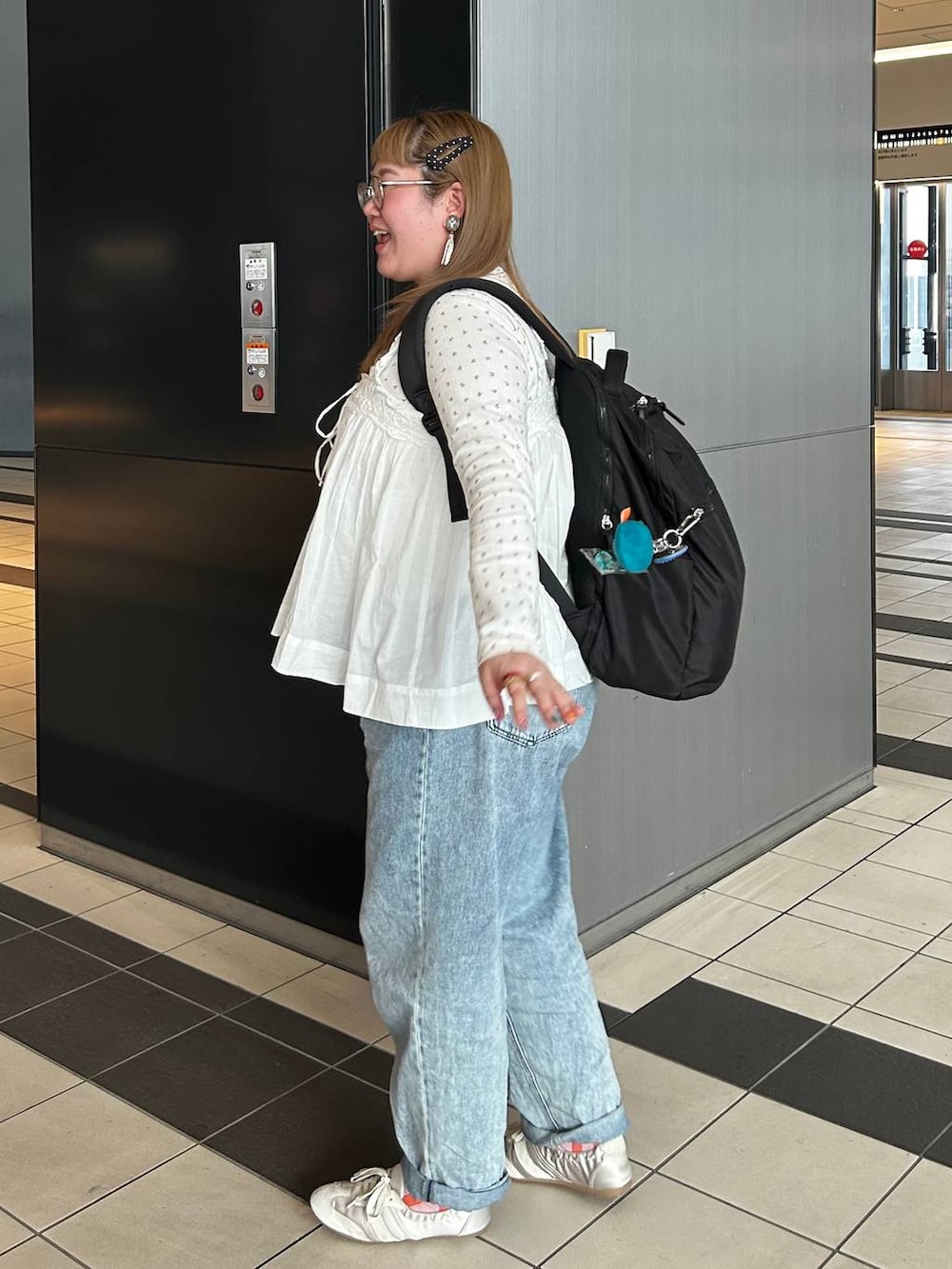 ブラック系のバックパック/リュック、ホワイト系のベスト、ブルー系のデニムパンツを着用したレディースの春コーディネートの3枚目の写真