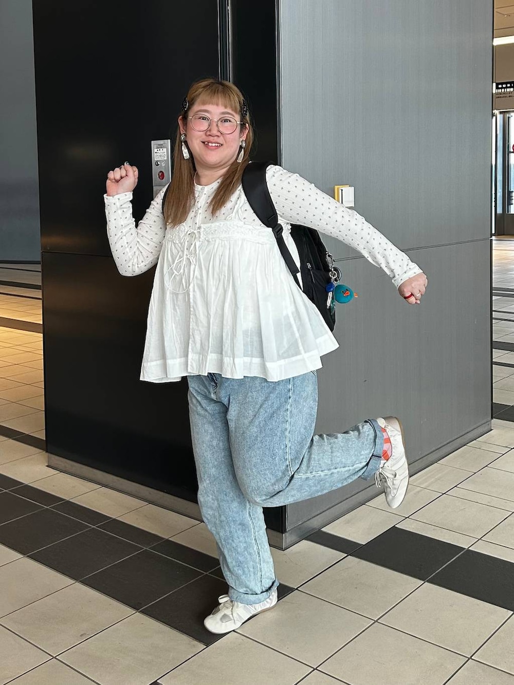 ブラック系のバックパック/リュック、ホワイト系のベスト、ブルー系のデニムパンツを着用したレディースの春コーディネートの6枚目の写真