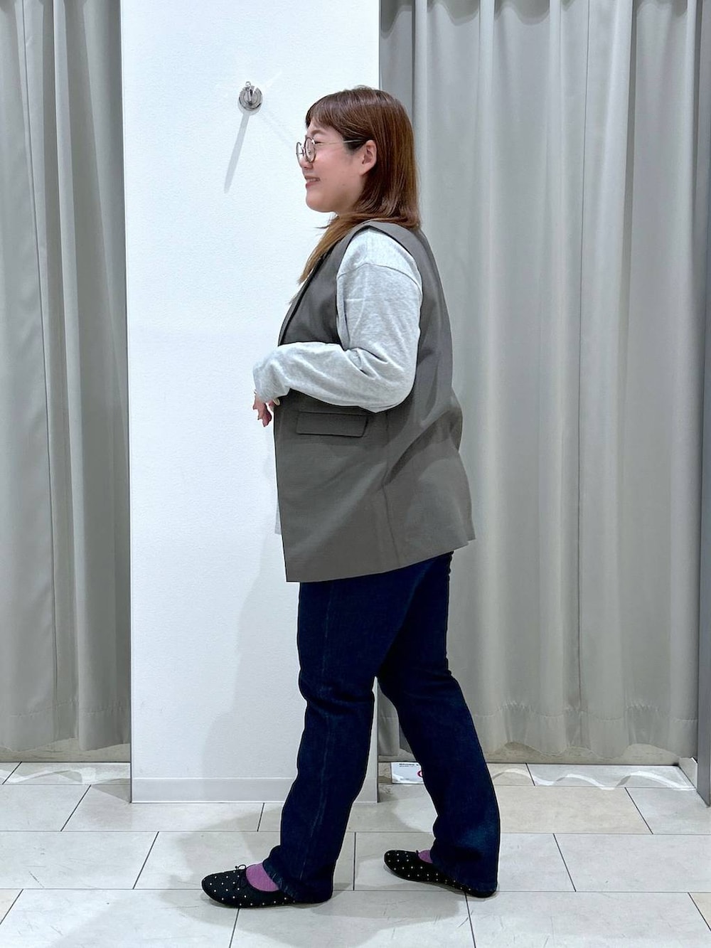 ブルー系のデニムパンツ、ブラック系のバレエシューズ、ブラウン系のベストを着用したレディースの秋コーディネートの4枚目の写真