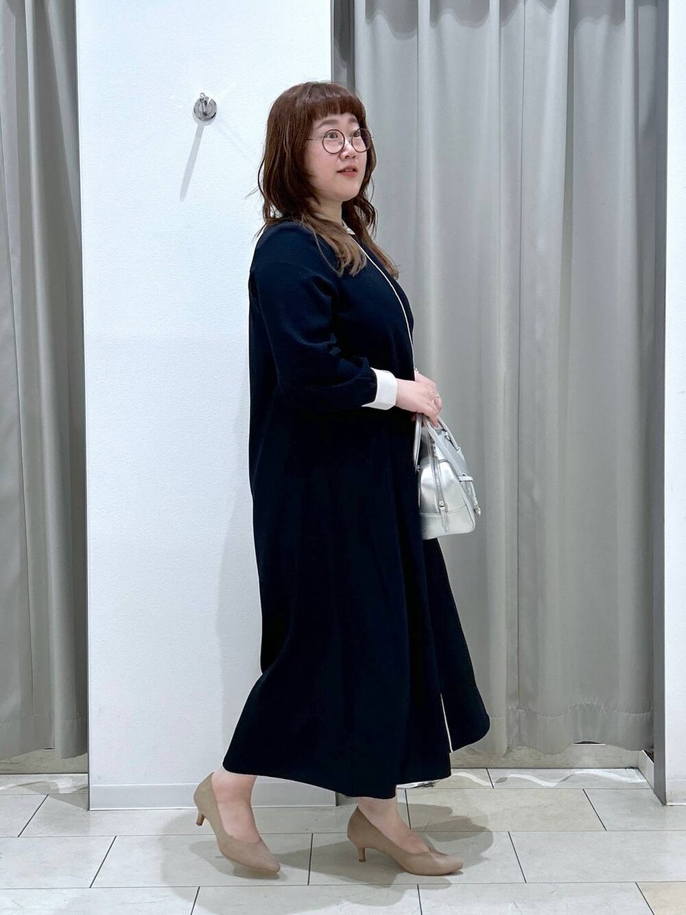 ブルー系のワンピース、ベージュ系のパンプス、シルバー系のボストンバッグを着用したレディースの秋コーディネートの7枚目の写真