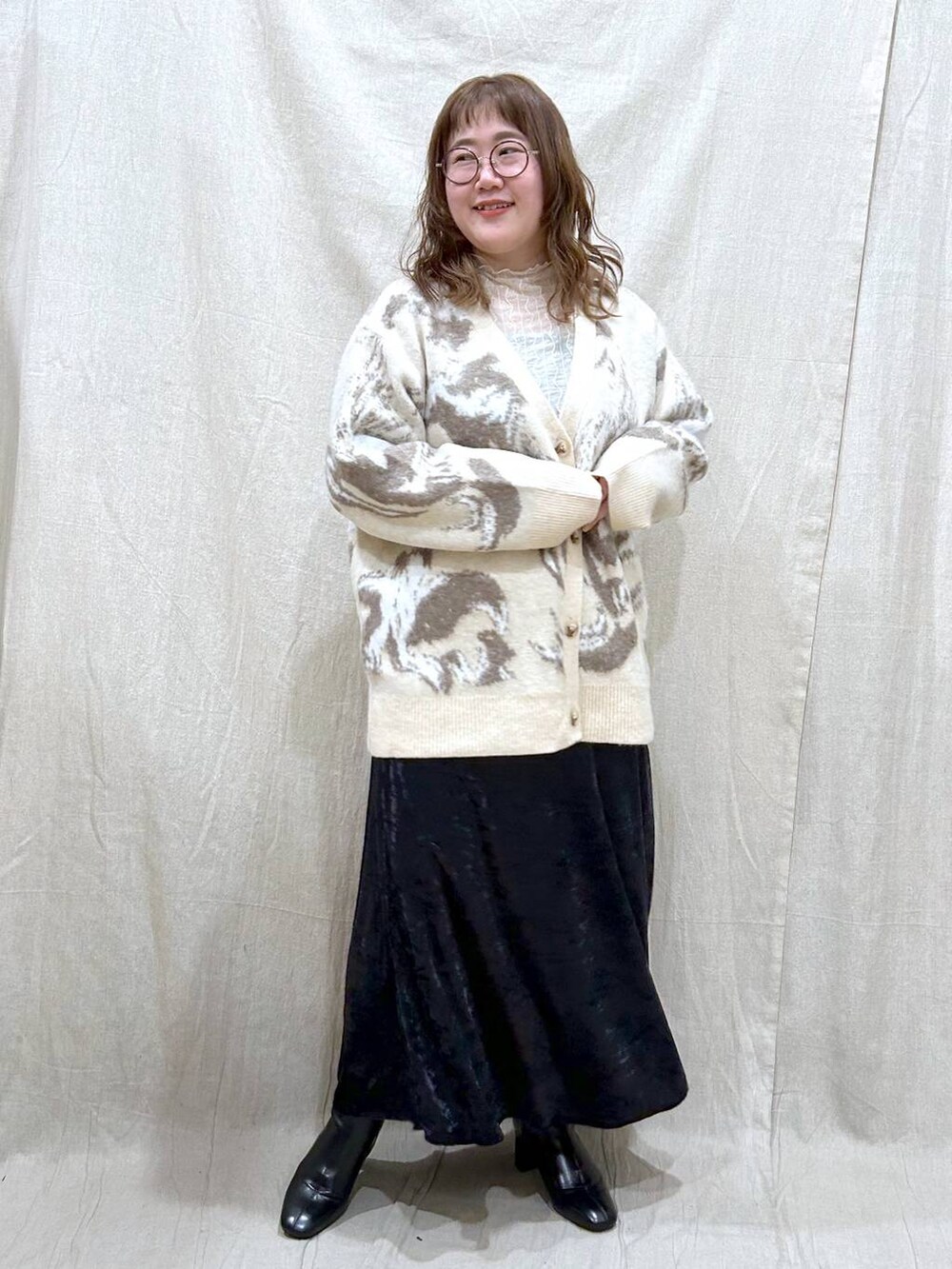 ブラック系のブーツ、ブラック系のスカート、ホワイト系のカーディガン/ボレロを着用したレディースの冬コーディネートの3枚目の写真