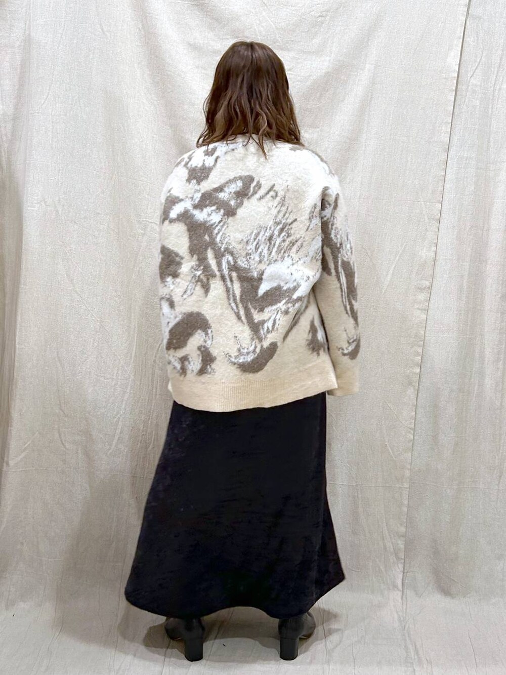 ブラック系のブーツ、ブラック系のスカート、ホワイト系のカーディガン/ボレロを着用したレディースの冬コーディネートの6枚目の写真