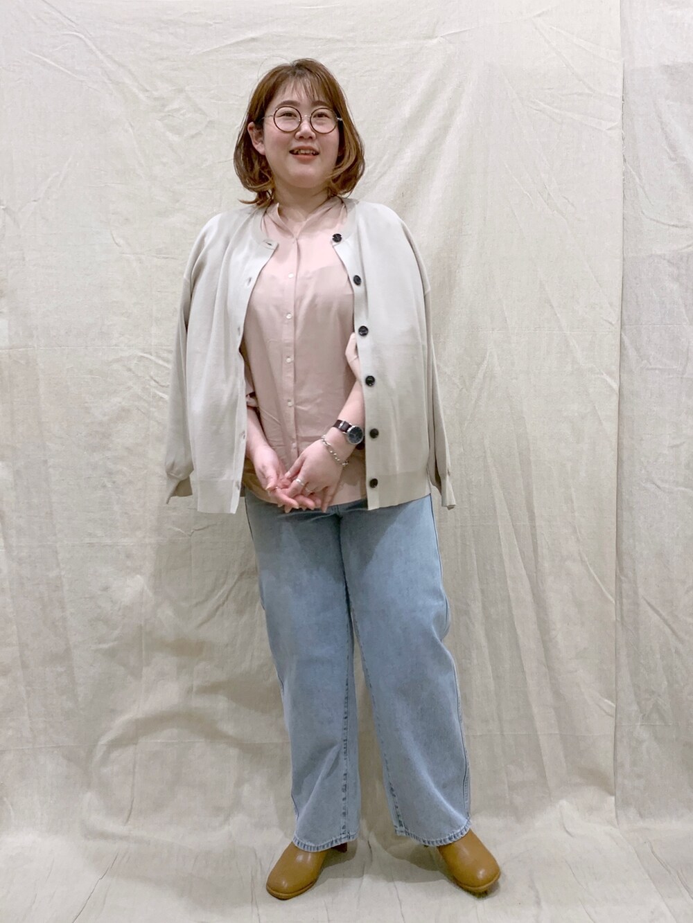 ベージュ系のカーディガン/ボレロ、オレンジ系のシャツ/ブラウス、ブルー系のデニムパンツを着用したレディースの春コーディネートの2枚目の写真