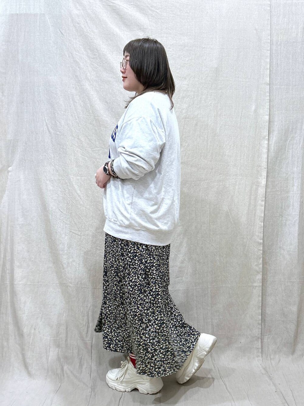 グレー系のスウェット、ホワイト系のスニーカー、ブラック系のワンピースを着用したレディースの春コーディネートの2枚目の写真