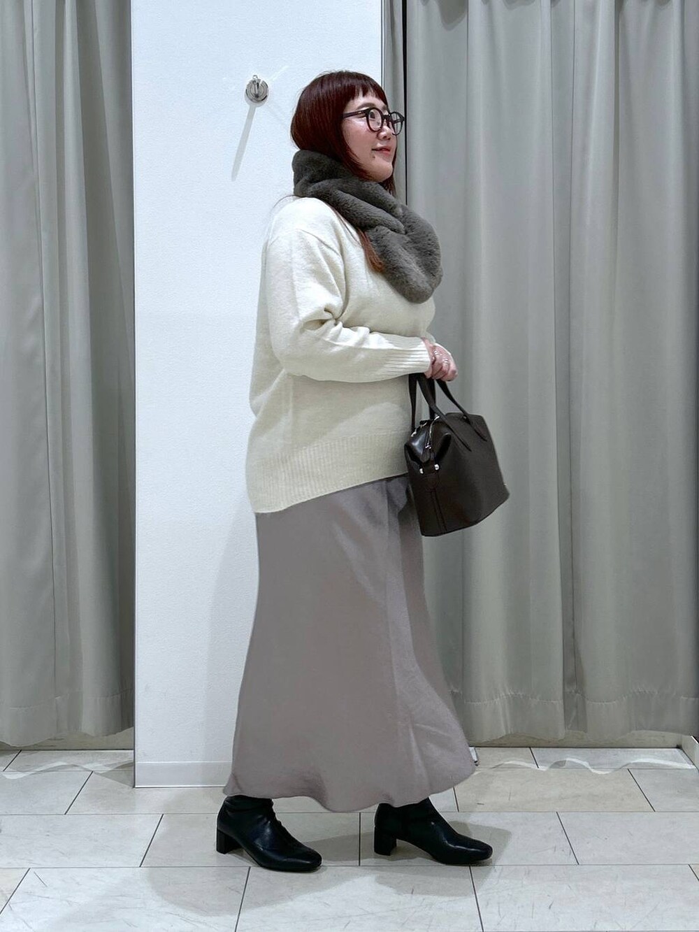 ホワイト系のニット/セーター、ブラック系のブーツ、ブラウン系のショルダーバッグを着用したレディースの冬コーディネートの6枚目の写真