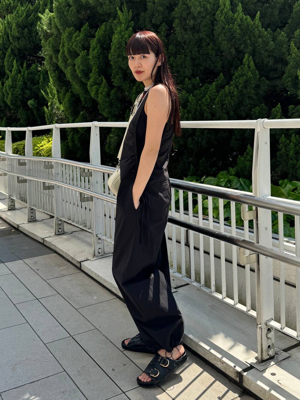 ホワイト系のショルダーバッグ、ブラック系のサロペット/オーバーオール、ブラック系のサンダルを着用したレディースの春コーディネートの6枚目の写真