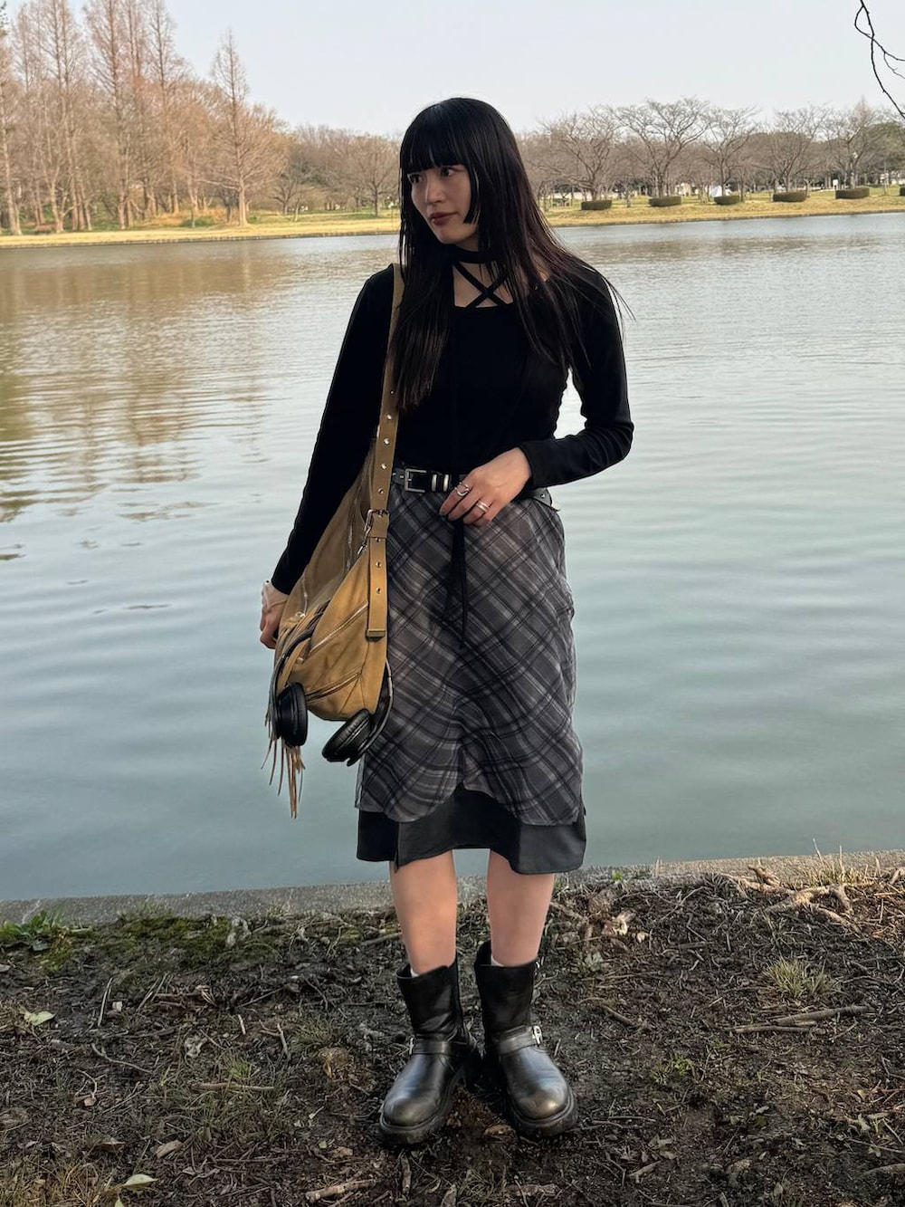 グリーン系のブーツ、ブラック系のスカート、ベージュ系のショルダーバッグを着用したレディースの春コーディネートの4枚目の写真