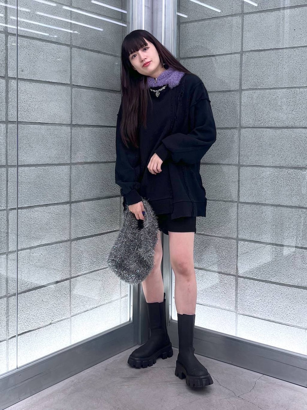 グレー系のハンドバッグ、ブラック系のスウェット、シルバー系のネックレスを着用したレディースの冬コーディネートの2枚目の写真