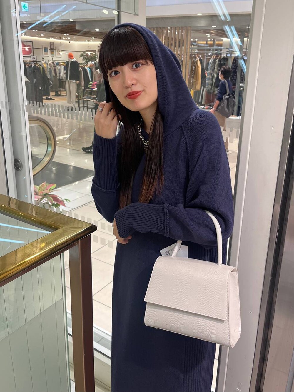 ホワイト系のハンドバッグ、ブラック系のブーツ、ブルー系のワンピースを着用したレディースの秋コーディネートの7枚目の写真