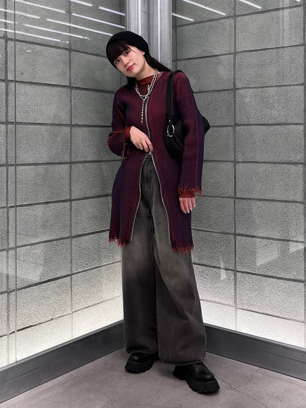 レッド系のワンピース、ブラック系のデニムパンツ、ブラック系のショルダーバッグを着用したレディースの冬コーディネートの3枚目の写真