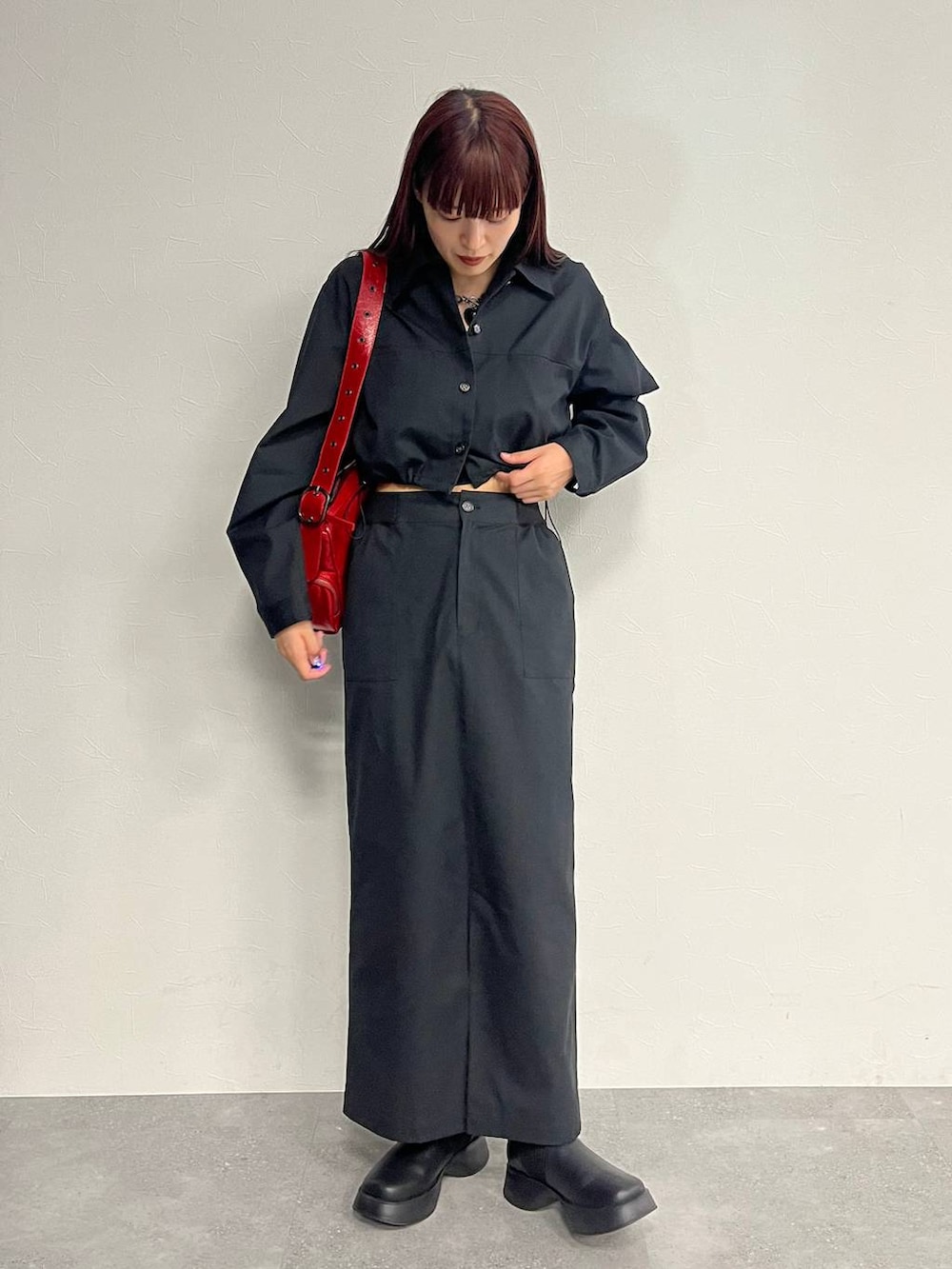 レッド系のショルダーバッグ、ブラック系のパンプス、ブラック系のセットアップを着用したレディースの秋コーディネートの3枚目の写真
