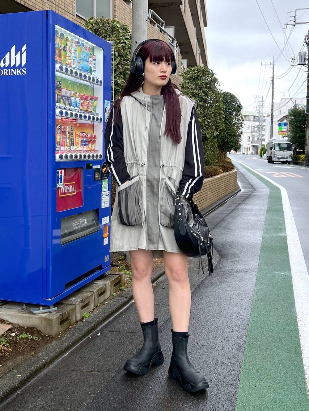 ブラック系のショルダーバッグ、ブラック系のTシャツ/カットソー、ブラック系のブーツを着用したレディースの冬コーディネートの2枚目の写真