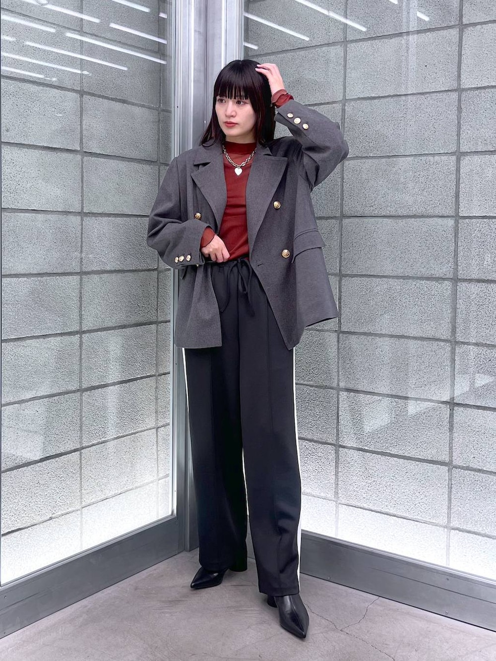 レッド系のTシャツ/カットソー、ブラック系のブーツ、ブルー系のテーラードジャケットを着用したレディースの冬コーディネートの2枚目の写真