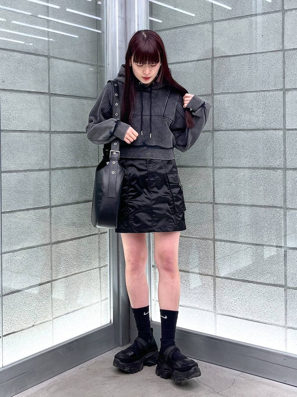 ブラック系のスカート、ブラック系のショルダーバッグ、ブラック系のパーカーを着用したレディースの冬コーディネートの2枚目の写真