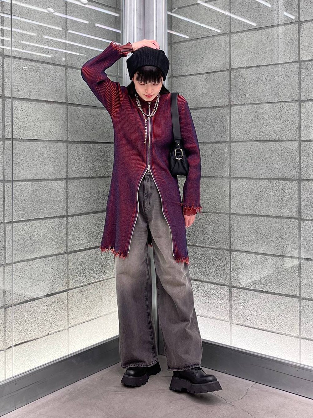 レッド系のワンピース、ブラック系のデニムパンツ、ブラック系のショルダーバッグを着用したレディースの冬コーディネートの2枚目の写真