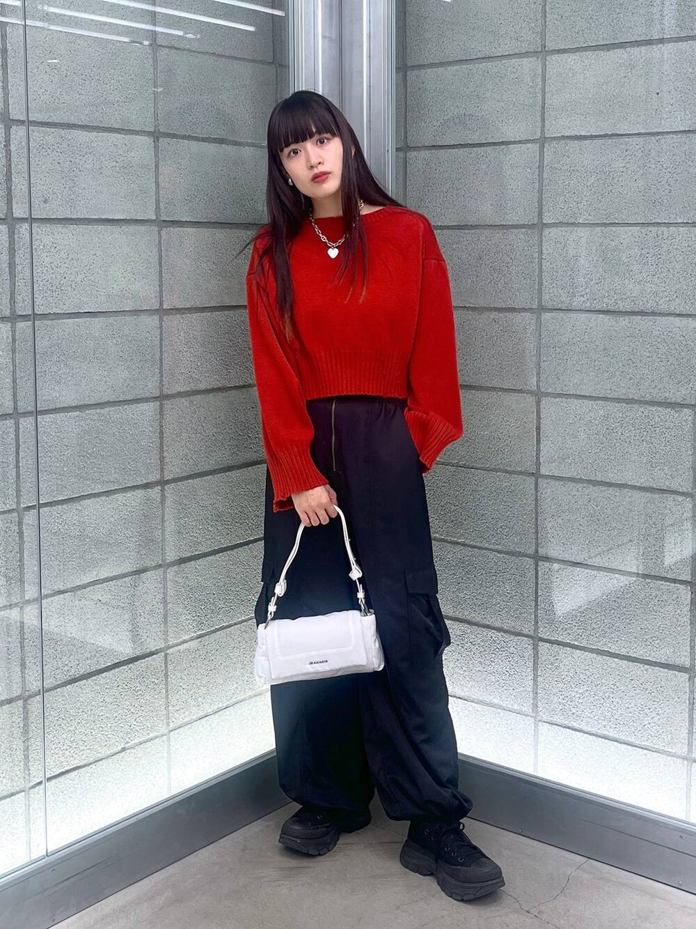 ブラック系のカーゴパンツ、ホワイト系のショルダーバッグ、レッド系のニット/セーターを着用したレディースの秋コーディネートの4枚目の写真