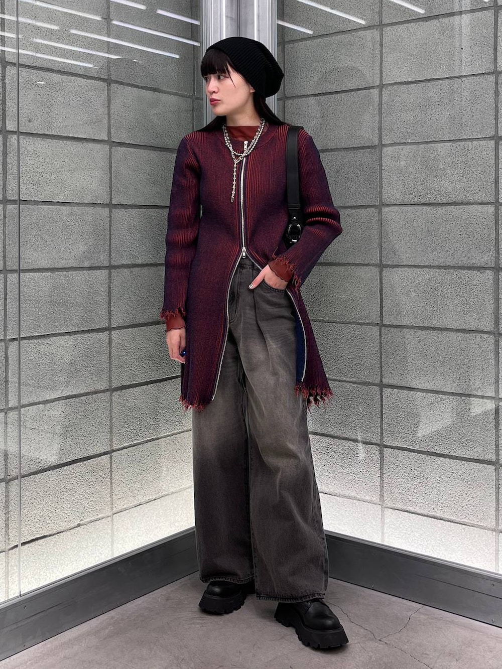 レッド系のワンピース、ブラック系のデニムパンツ、ブラック系のショルダーバッグを着用したレディースの冬コーディネートの7枚目の写真