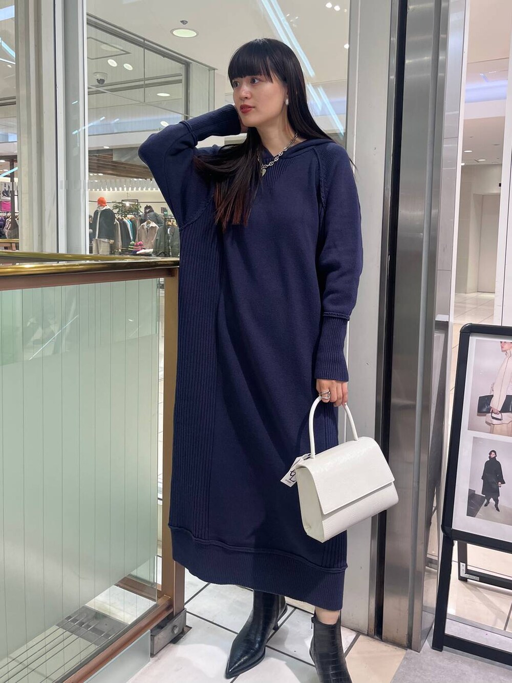 ホワイト系のハンドバッグ、ブラック系のブーツ、ブルー系のワンピースを着用したレディースの秋コーディネートの3枚目の写真