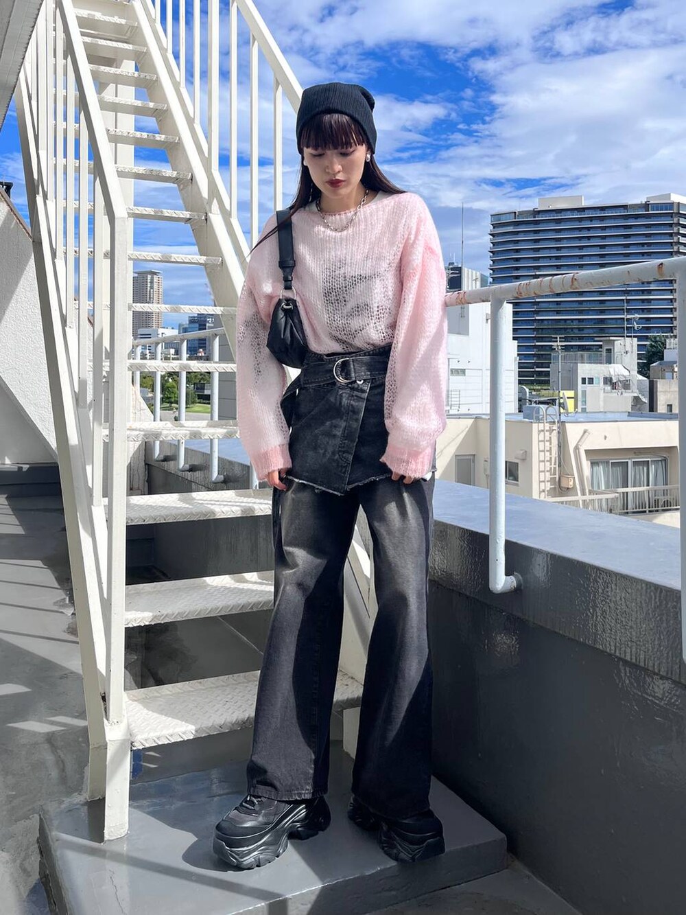 ブラック系のスニーカー、ブラック系のデニムパンツ、ブラック系のショルダーバッグを着用したレディースの秋コーディネートの5枚目の写真