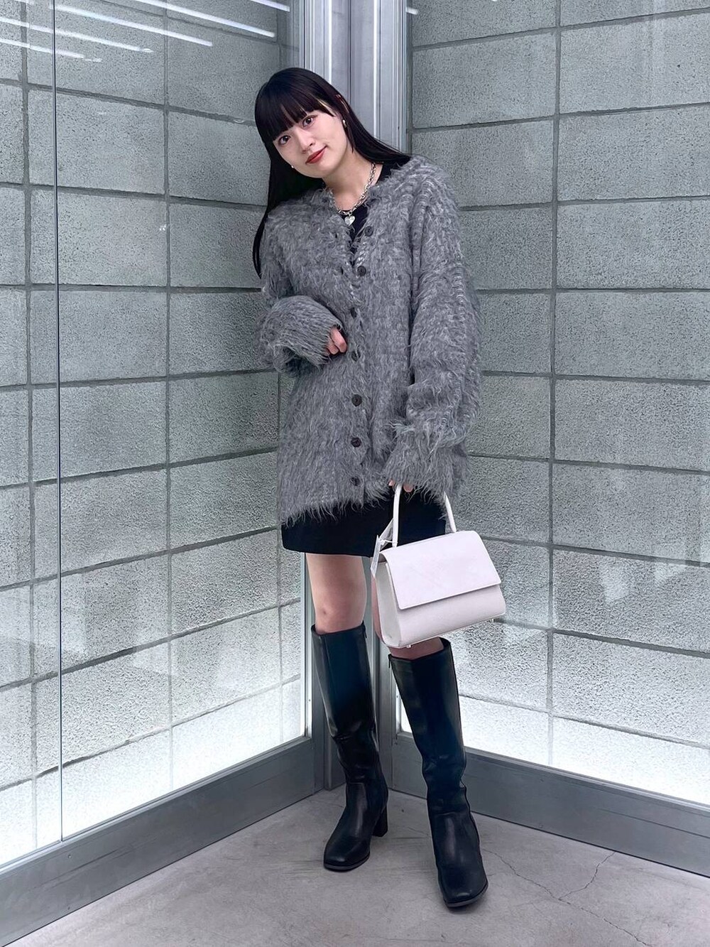 グレー系のカーディガン/ボレロ、ホワイト系のハンドバッグ、ブラック系のその他パンツを着用したレディースの秋コーディネートの3枚目の写真