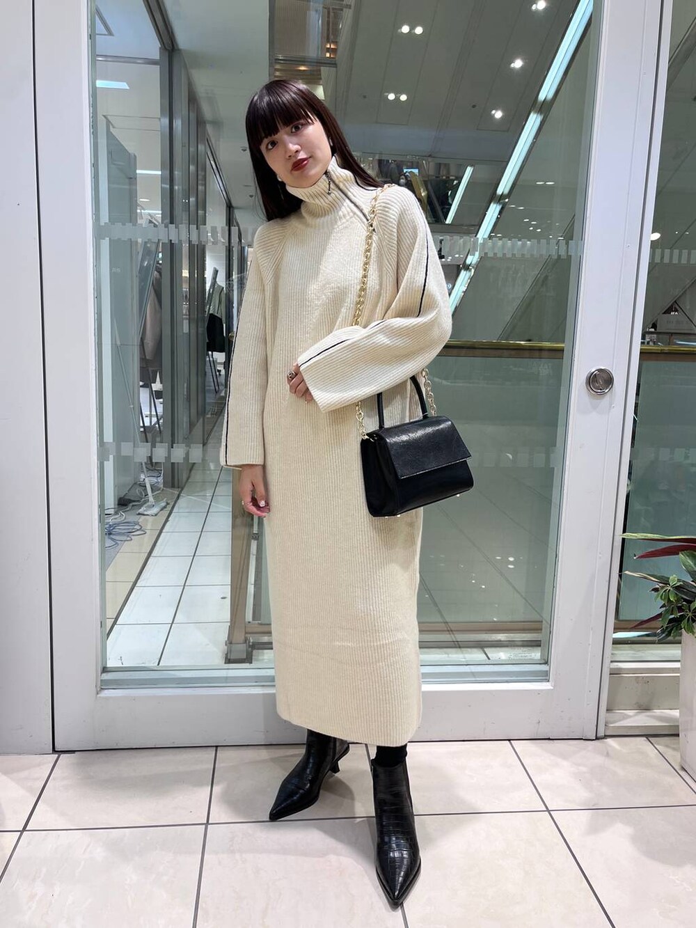 ブラック系のハンドバッグ、ブラック系のブーツ、ホワイト系のワンピースを着用したレディースの秋コーディネートの2枚目の写真