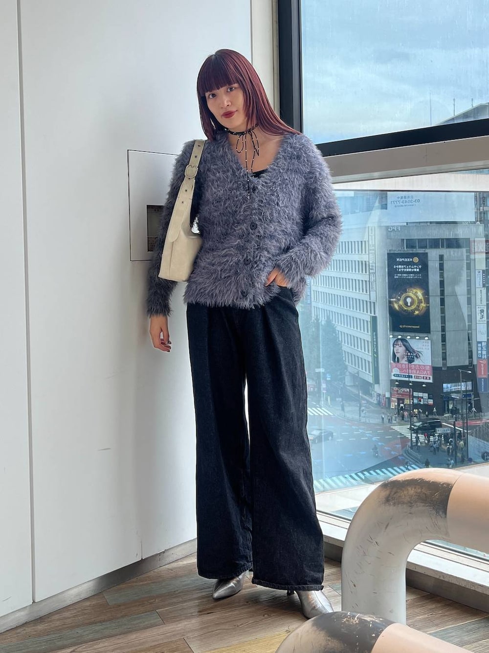 ホワイト系のショルダーバッグ、シルバー系のブーツ、ブラック系のデニムパンツを着用したレディースの秋コーディネートの3枚目の写真