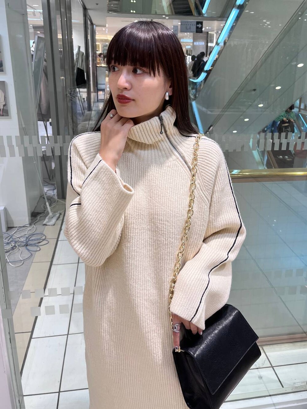 ブラック系のハンドバッグ、ブラック系のブーツ、ホワイト系のワンピースを着用したレディースの秋コーディネートの9枚目の写真