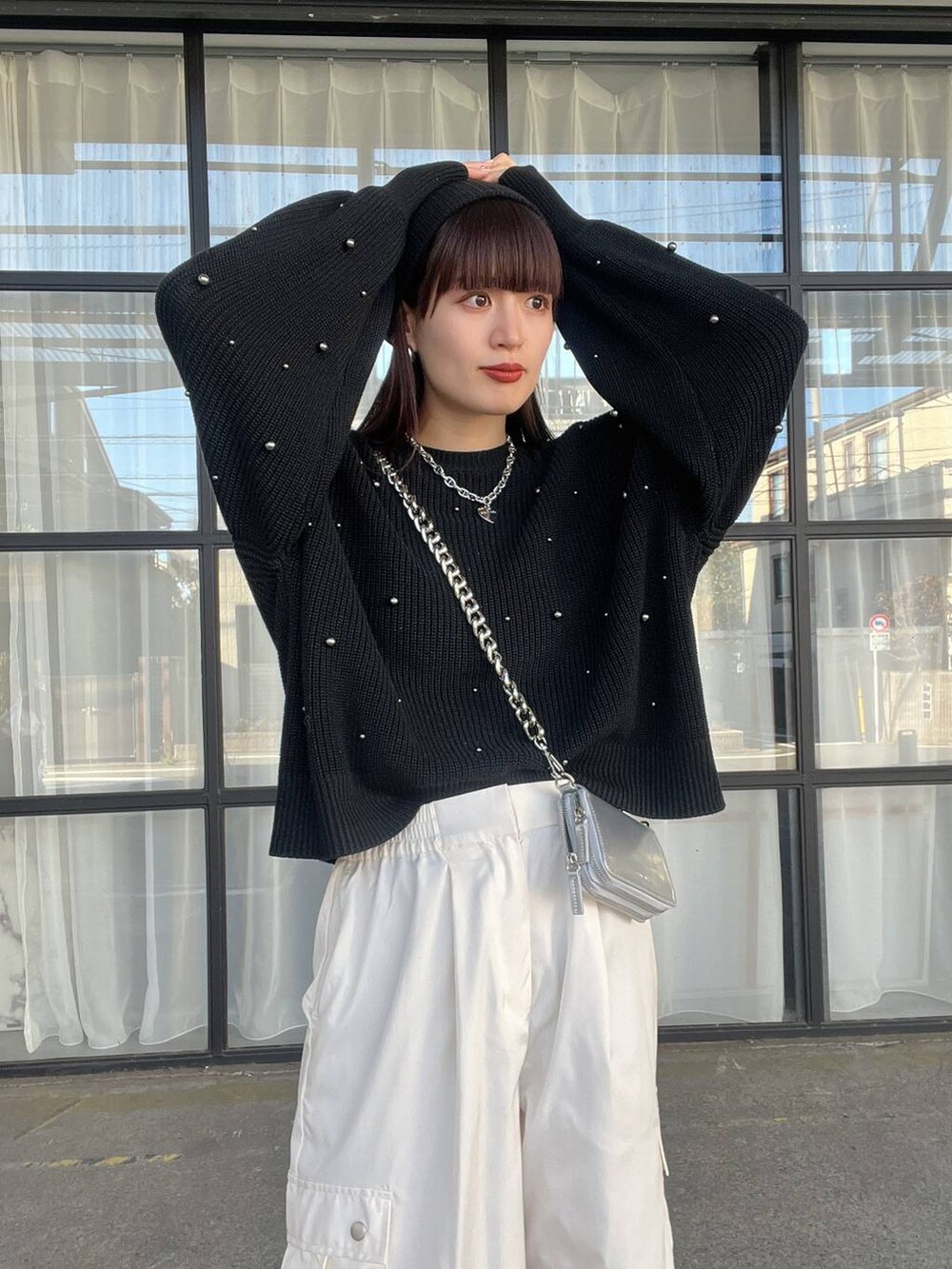 シルバー系のショルダーバッグ、ホワイト系のカーゴパンツ、ブラック系のニット/セーターを着用したレディースの秋コーディネートの2枚目の写真