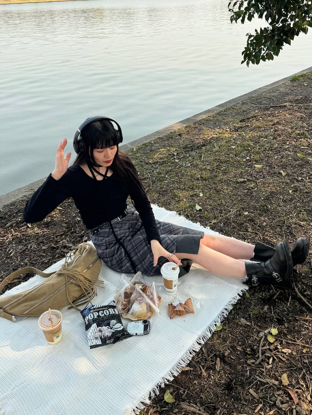 グリーン系のブーツ、ブラック系のスカート、ベージュ系のショルダーバッグを着用したレディースの春コーディネートの2枚目の写真