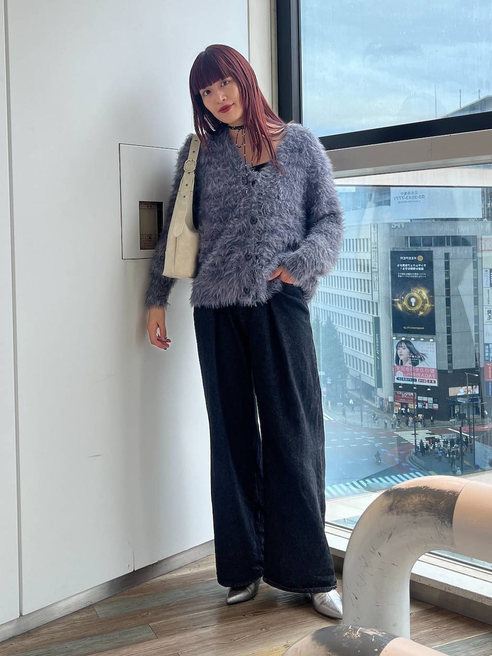 ホワイト系のショルダーバッグ、シルバー系のブーツ、ブラック系のデニムパンツを着用したレディースの秋コーディネートの2枚目の写真