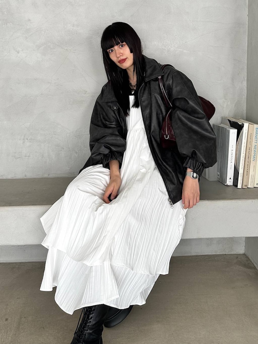 レッド系のボストンバッグ、ブラック系のブーツ、ホワイト系のワンピースを着用したレディースの冬コーディネートの2枚目の写真