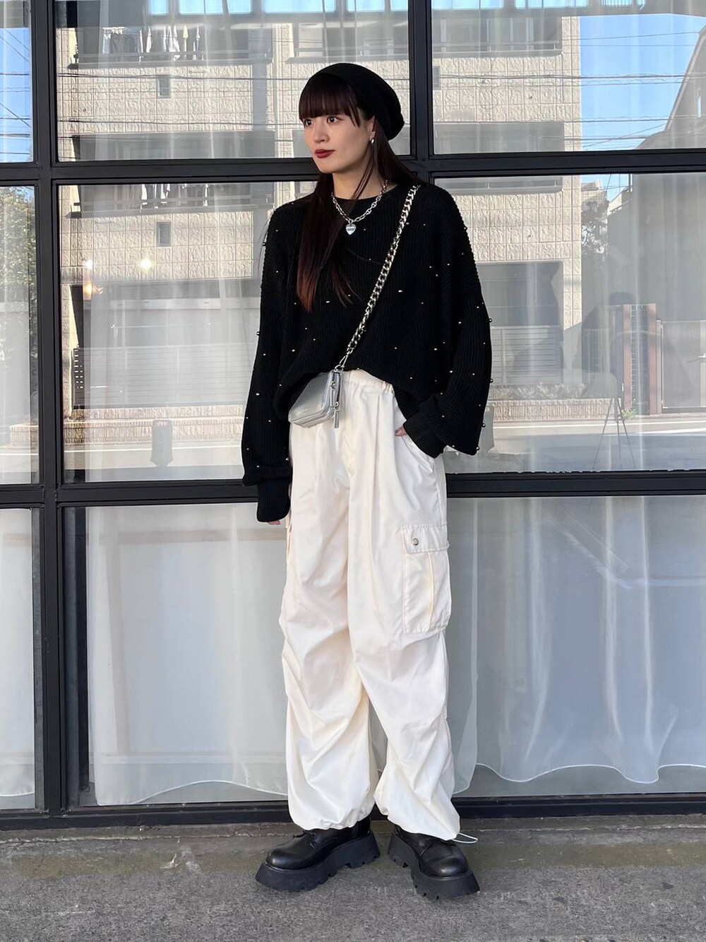 シルバー系のショルダーバッグ、ホワイト系のカーゴパンツ、ブラック系のニット/セーターを着用したレディースの秋コーディネートの5枚目の写真
