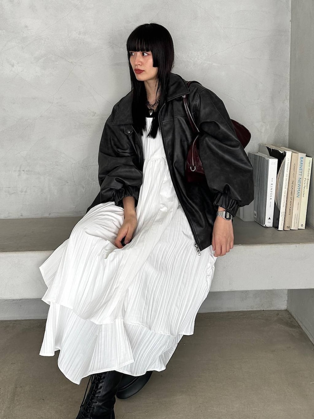 レッド系のボストンバッグ、ブラック系のブーツ、ホワイト系のワンピースを着用したレディースの冬コーディネートの3枚目の写真