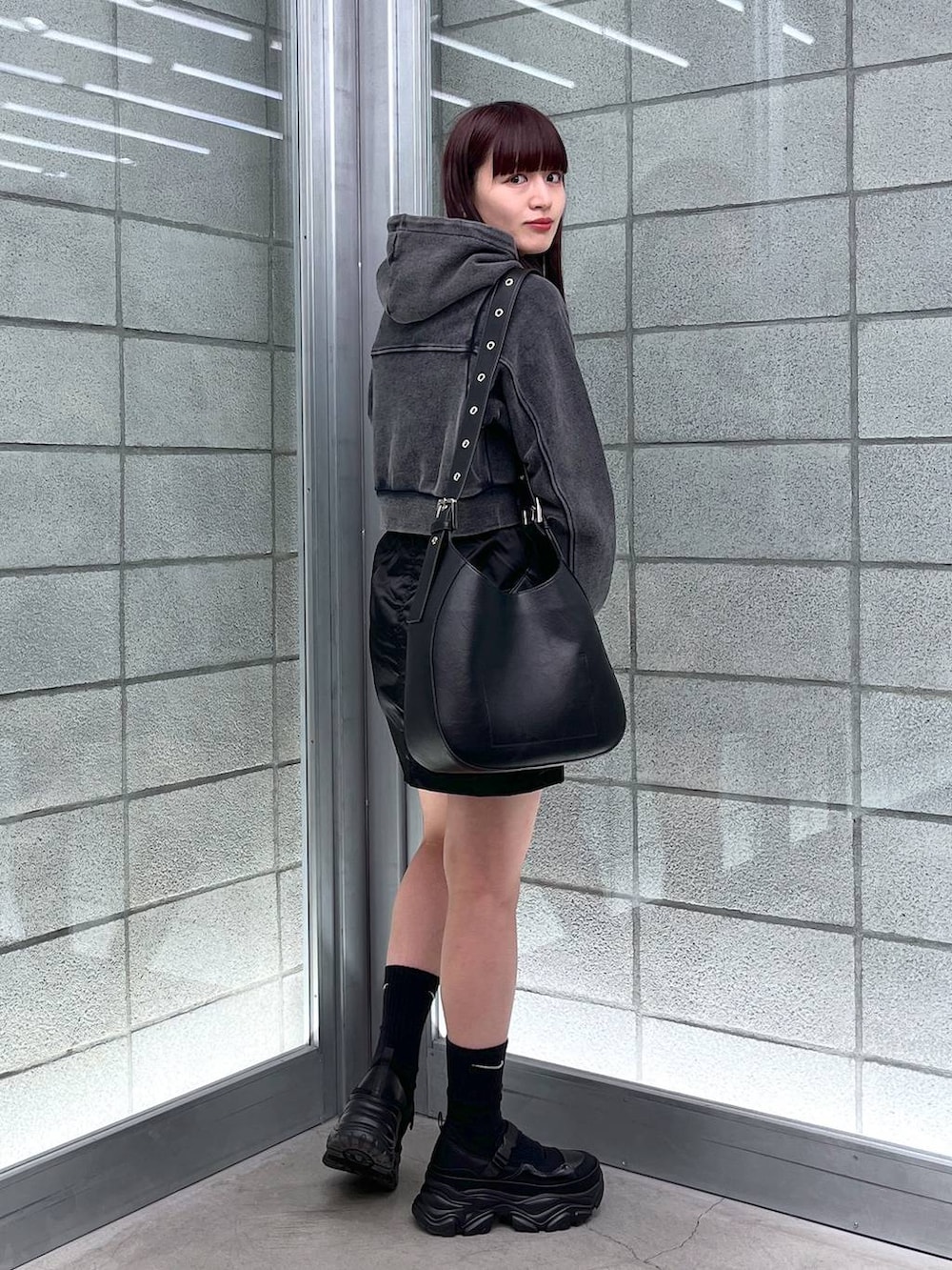 ブラック系のスカート、ブラック系のショルダーバッグ、ブラック系のパーカーを着用したレディースの冬コーディネートの3枚目の写真