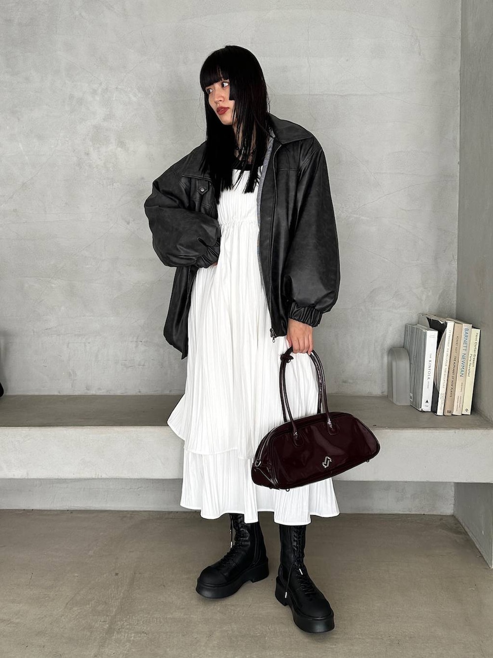 レッド系のボストンバッグ、ブラック系のブーツ、ホワイト系のワンピースを着用したレディースの冬コーディネートの4枚目の写真