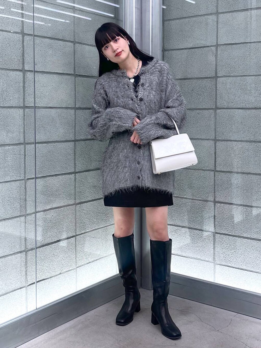 グレー系のカーディガン/ボレロ、ホワイト系のハンドバッグ、ブラック系のその他パンツを着用したレディースの秋コーディネートの2枚目の写真