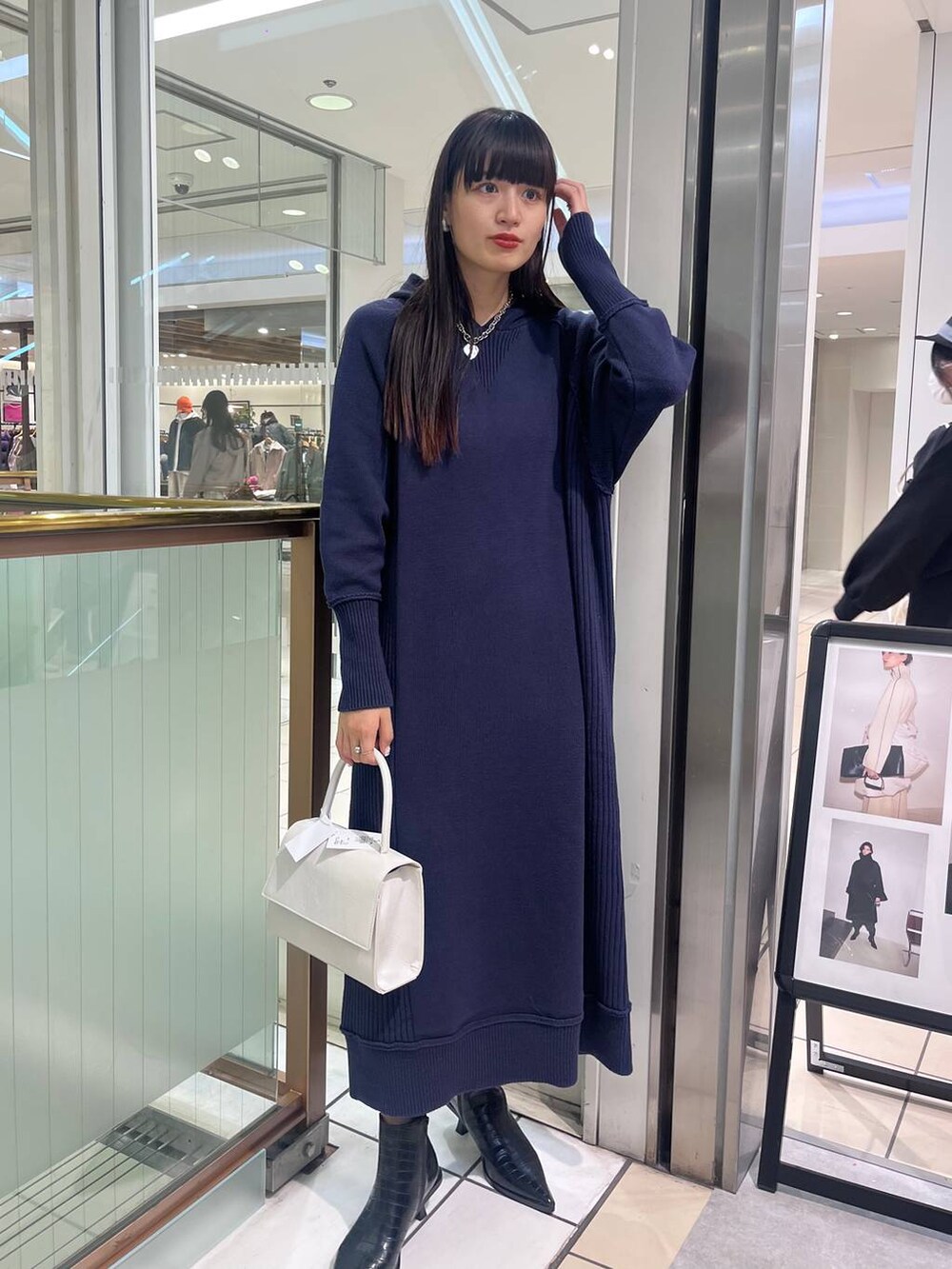 ホワイト系のハンドバッグ、ブラック系のブーツ、ブルー系のワンピースを着用したレディースの秋コーディネートの2枚目の写真