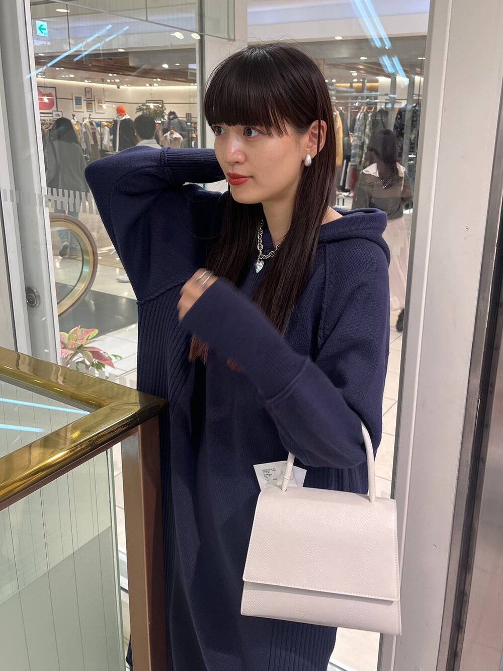 ホワイト系のハンドバッグ、ブラック系のブーツ、ブルー系のワンピースを着用したレディースの秋コーディネートの6枚目の写真