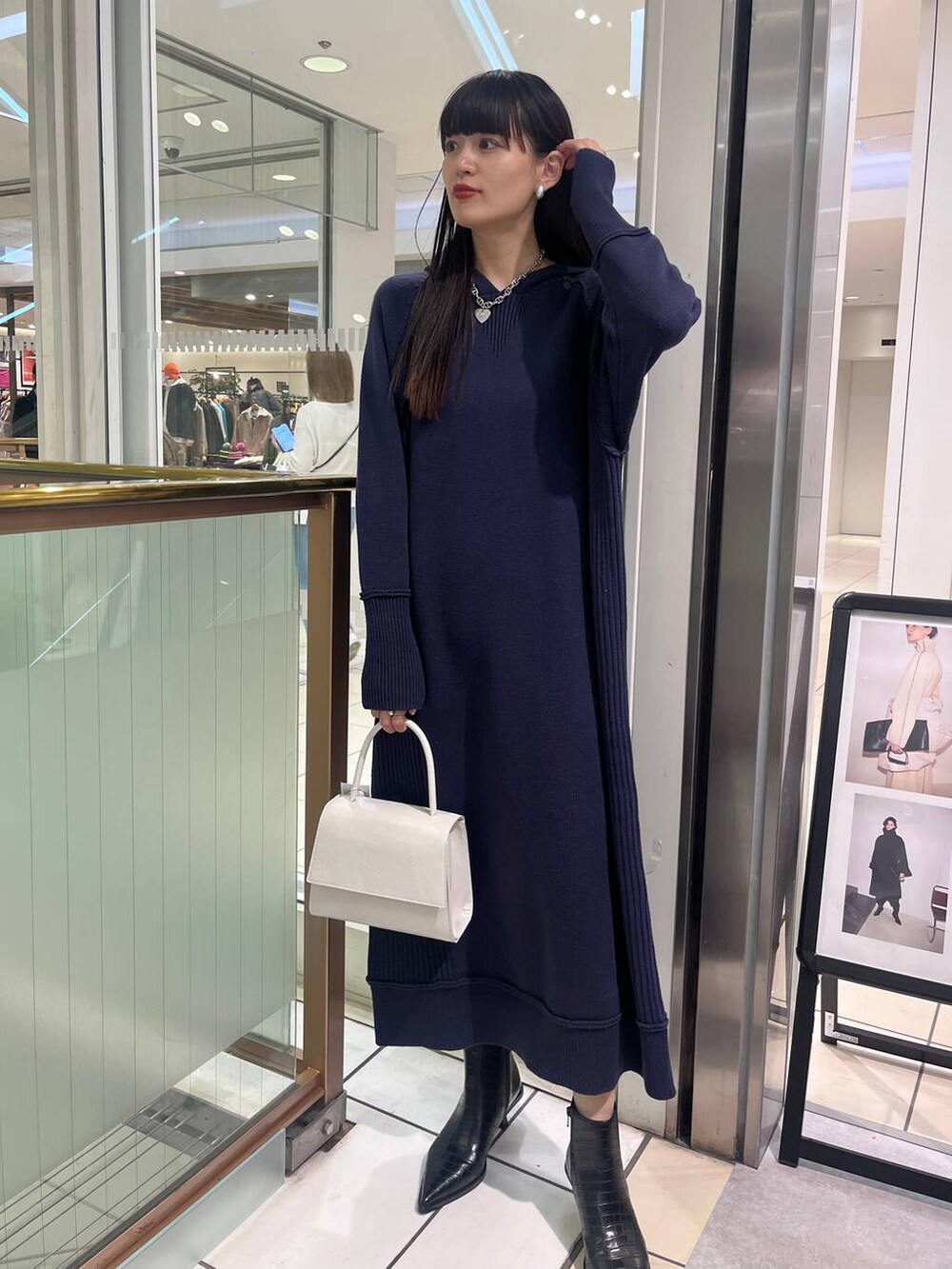 ホワイト系のハンドバッグ、ブラック系のブーツ、ブルー系のワンピースを着用したレディースの秋コーディネートの4枚目の写真