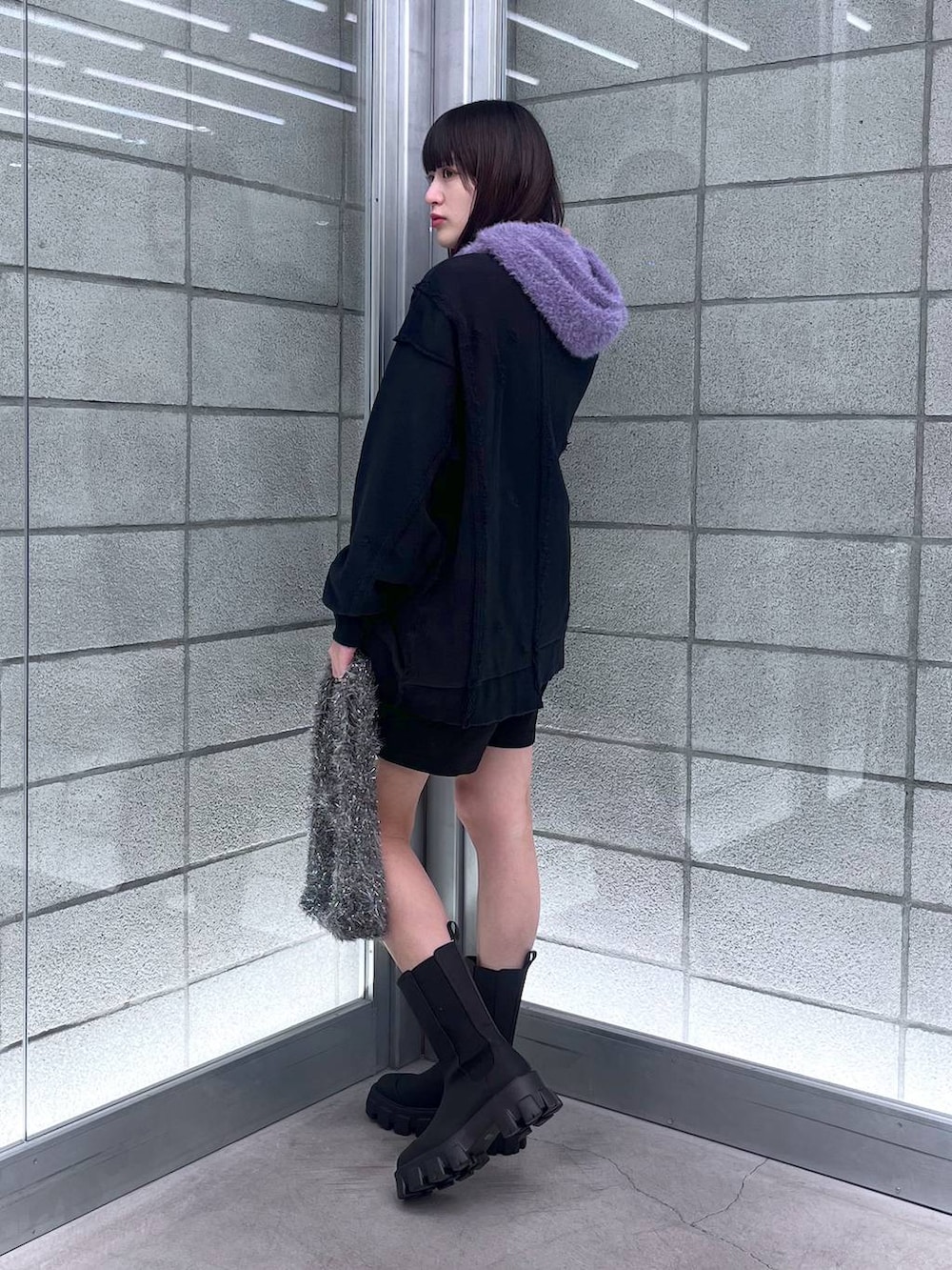 グレー系のハンドバッグ、ブラック系のスウェット、シルバー系のネックレスを着用したレディースの冬コーディネートの3枚目の写真