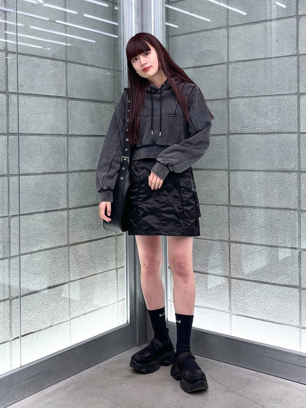 ブラック系のスカート、ブラック系のショルダーバッグ、ブラック系のパーカーを着用したレディースの冬コーディネートの5枚目の写真