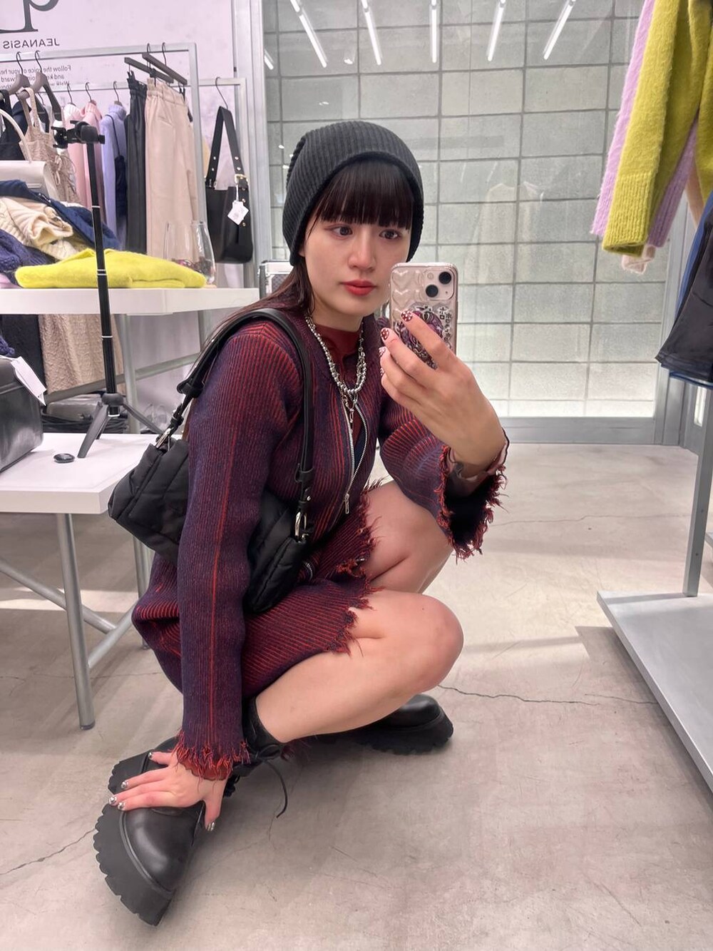 レッド系のワンピース、ブラック系のデニムパンツ、ブラック系のショルダーバッグを着用したレディースの冬コーディネートの5枚目の写真